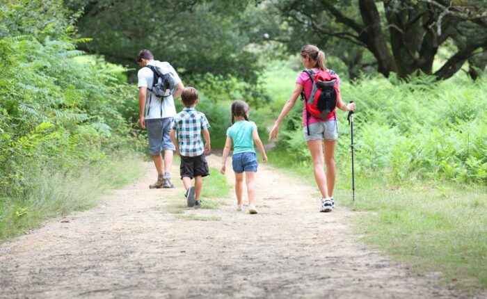 Couple avec ses 2 enfants se promenant dans ce qui semble être une forêt.