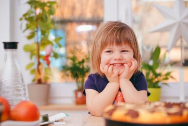Jeune enfant souriant devant un gâteau.