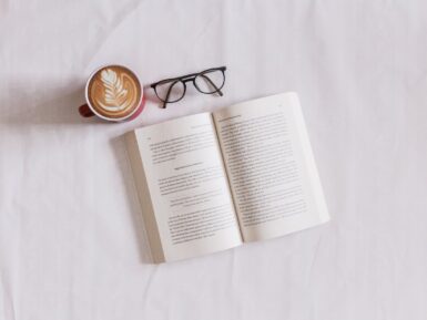 Livre ouvert sur une table avec une tasse de café et des lunettes.