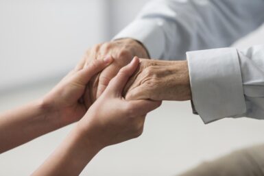 Mains d'une personne âgée tenant les mains d'une personne plus jeune.