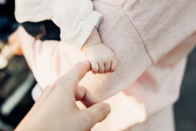 Bébé à bras et serrant la main d'un adulte.